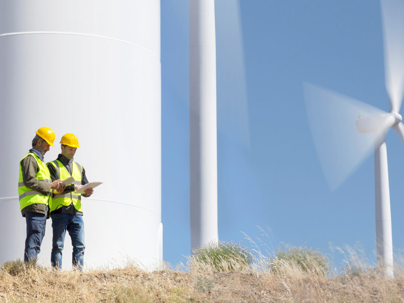 Workers talking by wind turbines