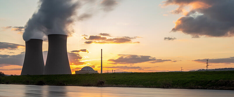 Nuclear power plant against sky by the river at sunset